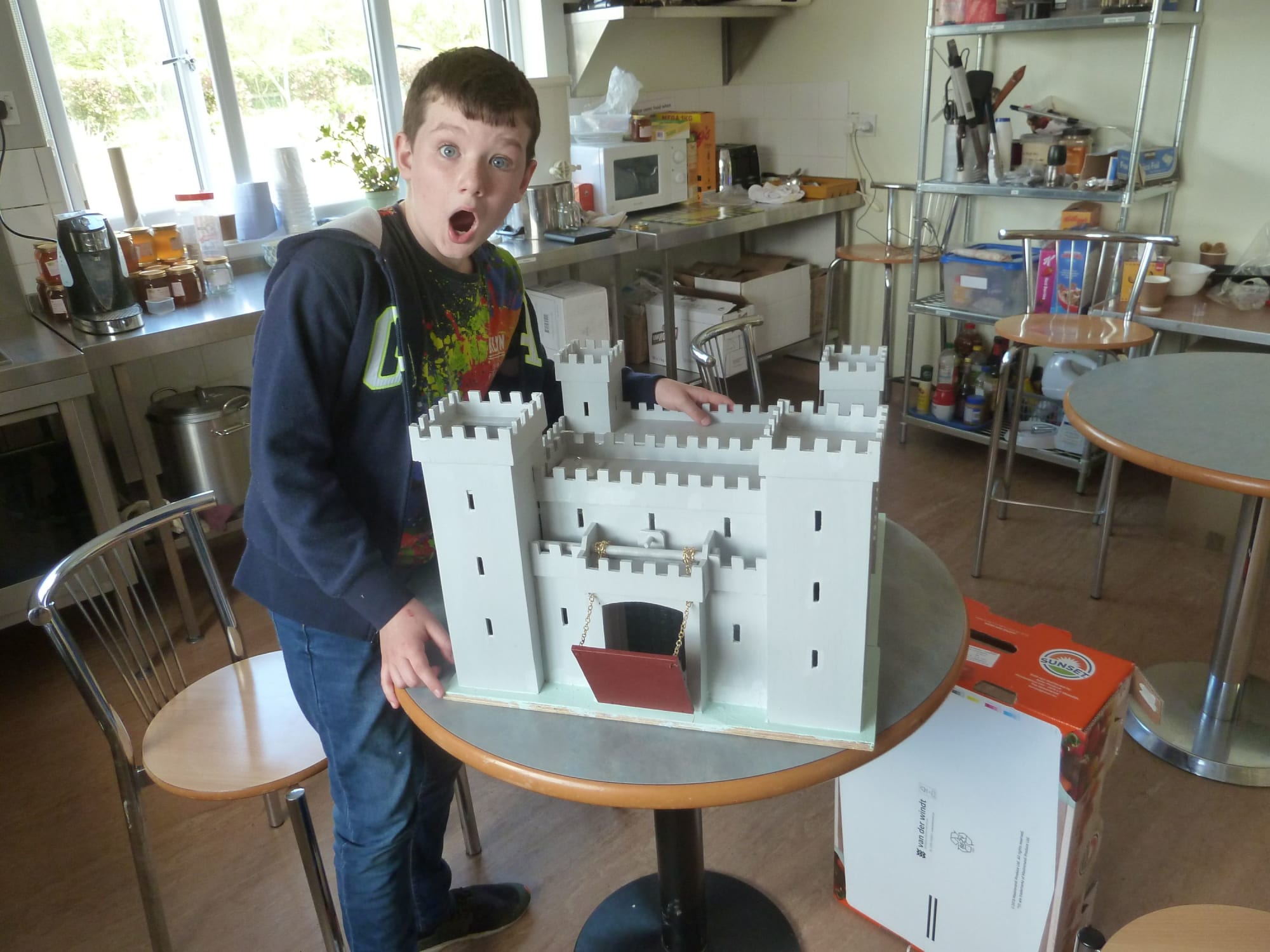 A young person poses with the toy castle he built in woodworking sessions.